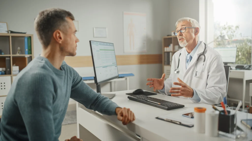 A man sitting at a table talking to a doctor.